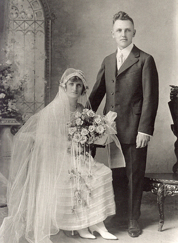 Portrait classique de mariés, avec l'homme debout et la femme assise